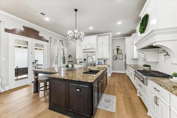a kitchen with granite countertop kitchen island stainless steel appliances a sink stove and cabinets