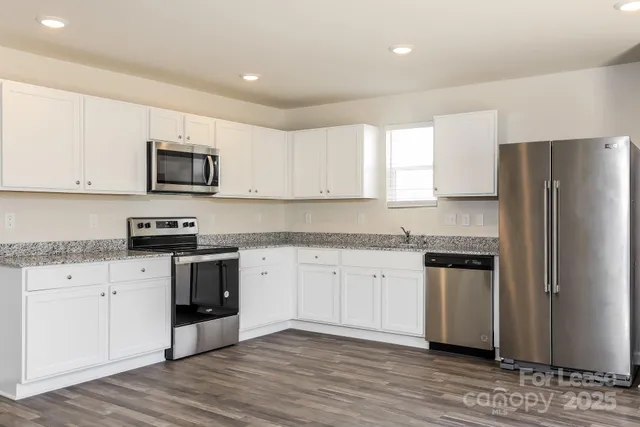a kitchen with granite countertop a refrigerator and a stove top oven