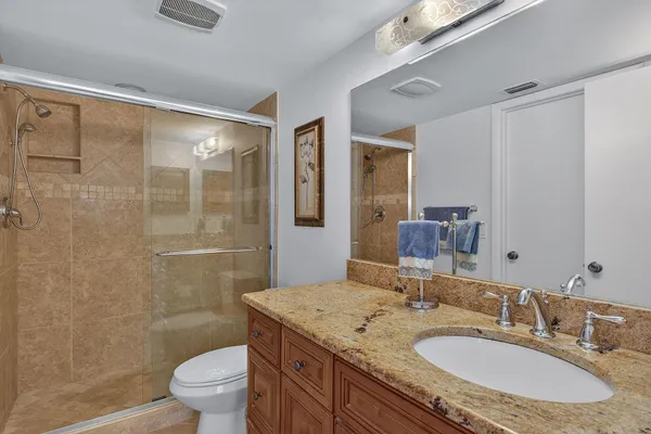 a bathroom with a granite countertop sink a toilet a mirror and shower
