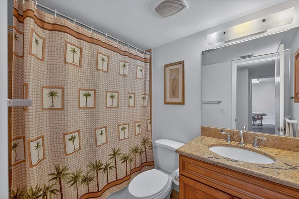 a bathroom with a granite countertop sink mirror vanity and toilet