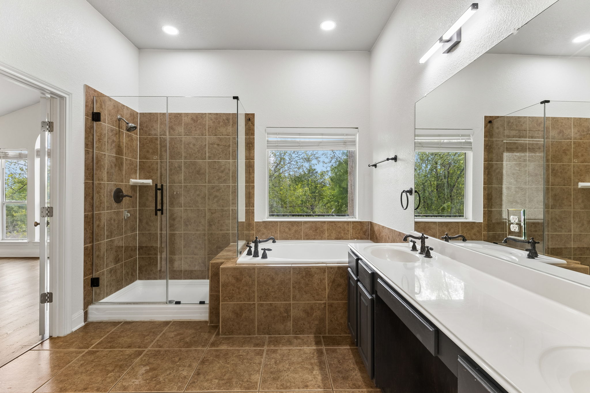 114 Aria Ridge, Unit 802 Lakeway, TX 78738 - Photo 26 of 37 A well-appointed primary bathroom features a generous soaking tub, a separate tiled shower, and a double vanity.