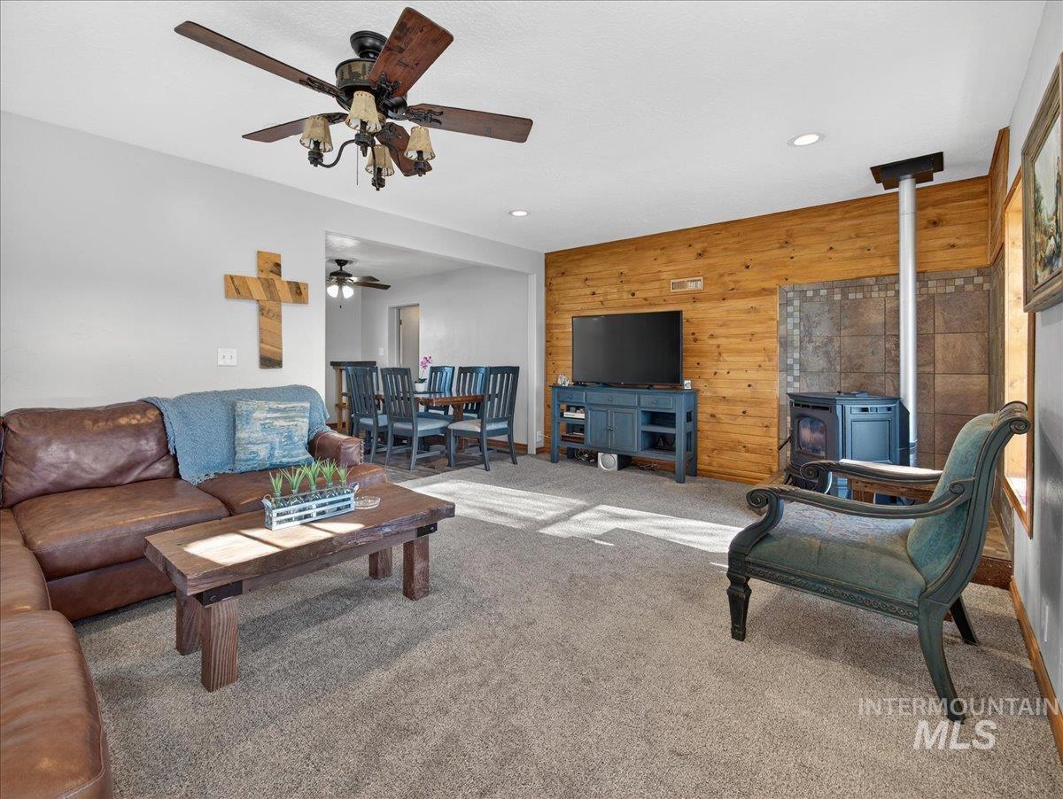 2588 West Sales Yard Road Emmett, ID 83617 - Photo 13 of 50 Carpeted living room featuring wooden walls, a wood stove, recessed lighting, and an accent wall