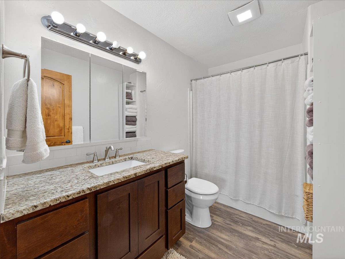 2588 West Sales Yard Road Emmett, ID 83617 - Photo 29 of 50 Full bathroom featuring dark wood-style flooring, vanity, shower / bath combination with curtain, and a textured ceiling