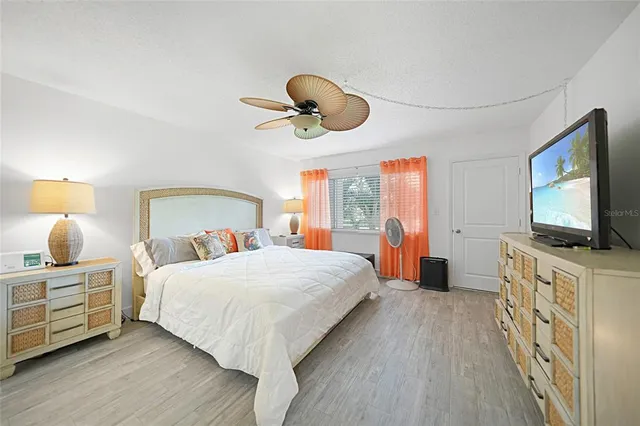 a bedroom with a bed chandelier and a large window