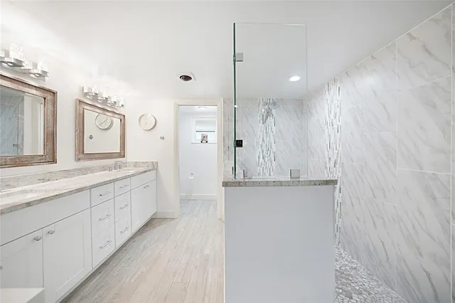 a bathroom with a granite countertop double vanity sink and a mirror