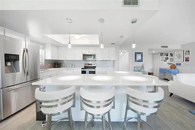 a kitchen with kitchen island granite countertop a sink and white cabinets with wooden floor