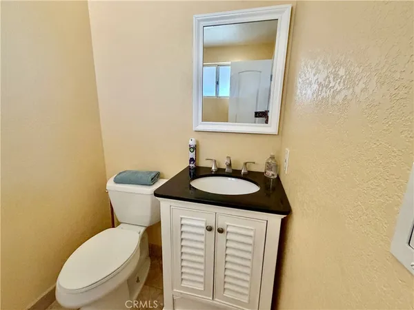 a bathroom with a granite countertop toilet sink and mirror