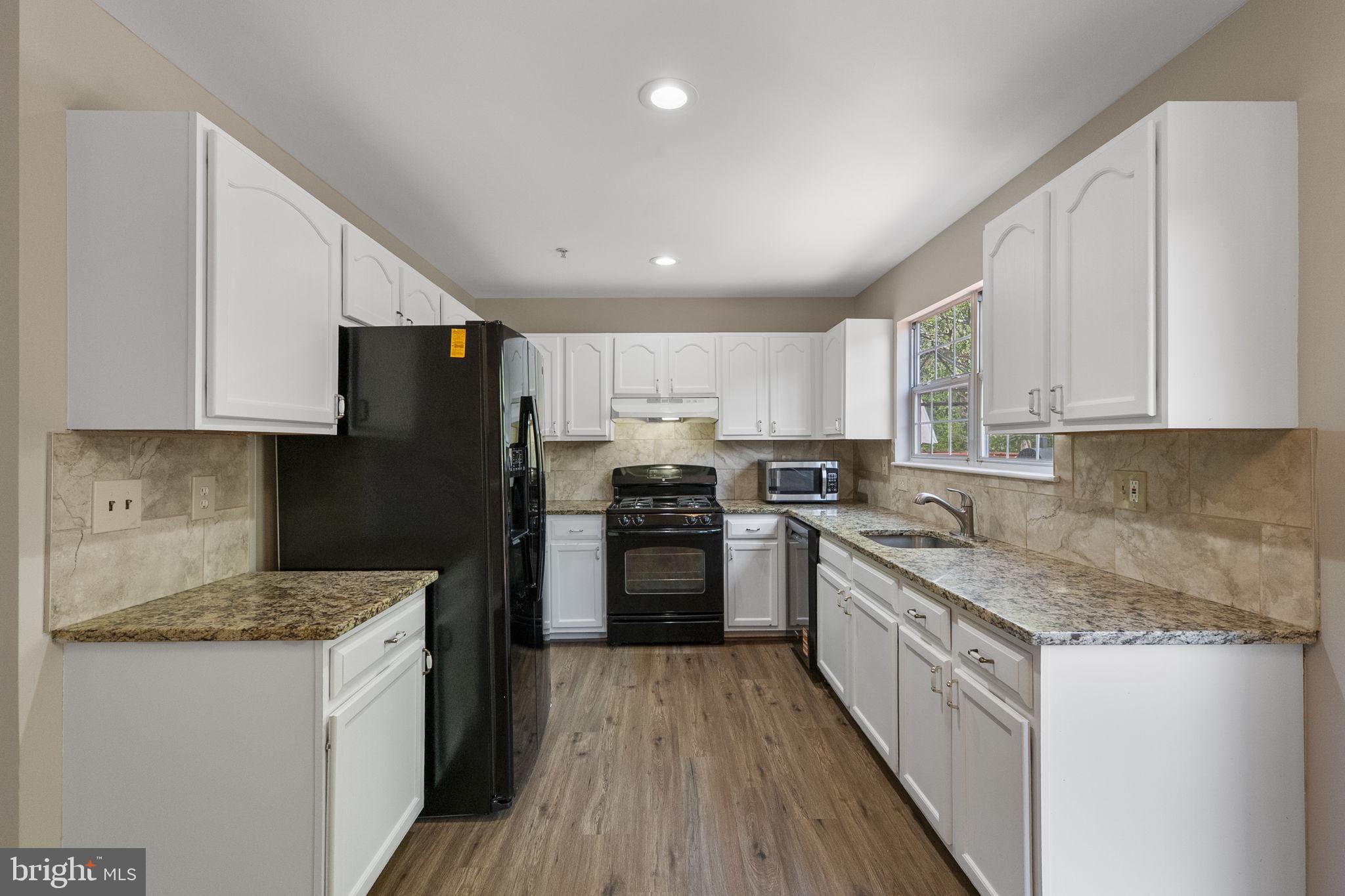3514 Corn Stream Road Randallstown, MD 21133 - Photo 17 of 44 a kitchen with stainless steel appliances granite countertop a stove a sink dishwasher a refrigerator and white cabinets with wooden floor