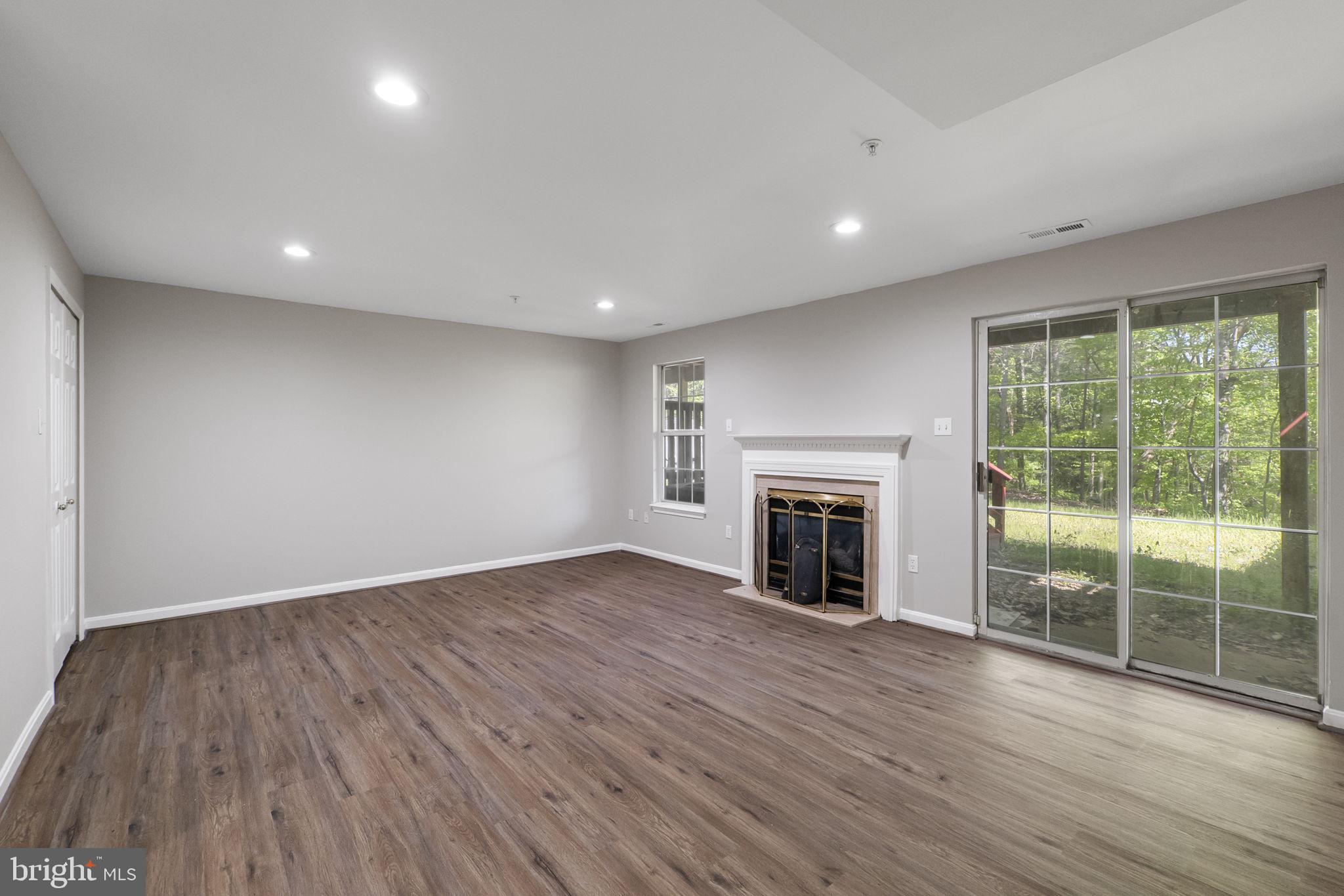 3514 Corn Stream Road Randallstown, MD 21133 - Photo 32 of 44 an empty room with wooden floor fireplace and windows
