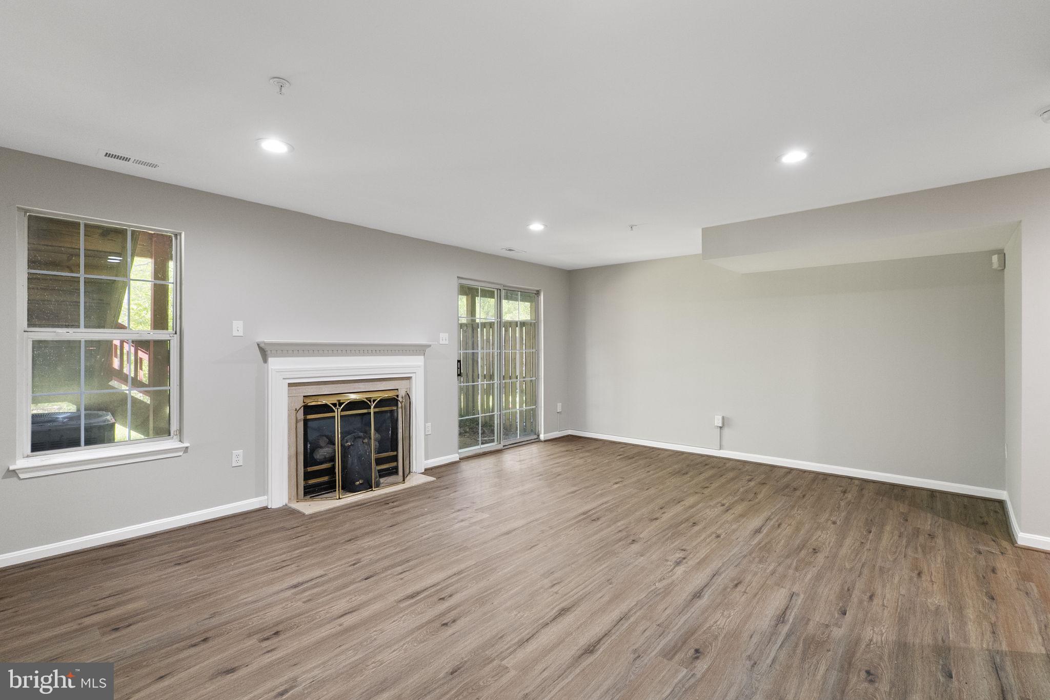 3514 Corn Stream Road Randallstown, MD 21133 - Photo 34 of 44 an empty room with wooden floor fireplace and windows