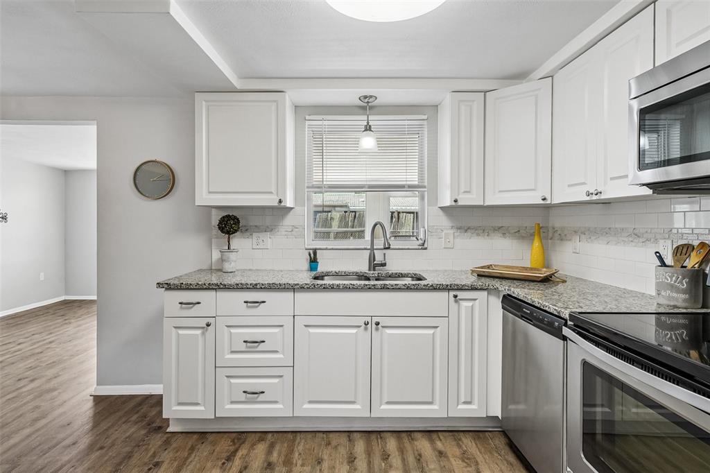 7215 Mayfield Drive Port Richey, FL 34668 - Photo 31 of 52 a kitchen with granite countertop white cabinets and stainless steel appliances
