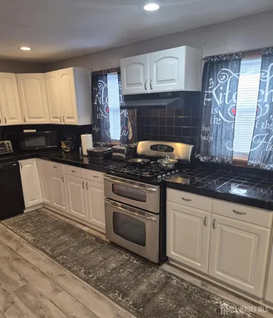 a kitchen with granite countertop a sink a stove and cabinets
