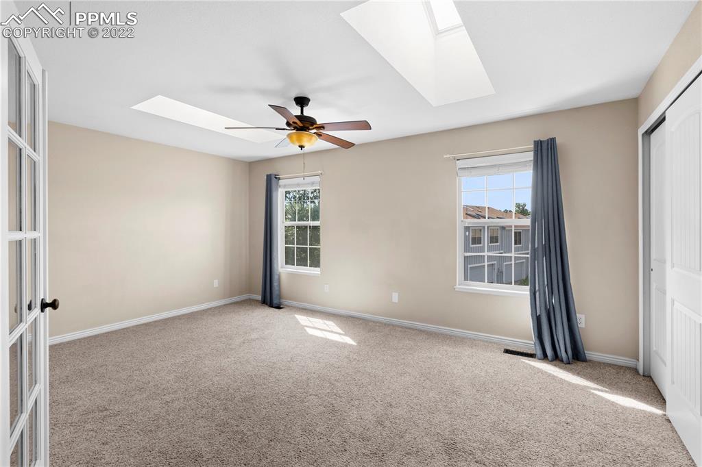 6910 Los Reyes Circle Colorado Springs, CO 80918 - Photo 11 of 38 an empty room with windows and chandelier fan