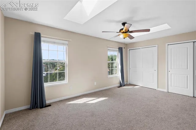 an empty room with windows and chandelier fan