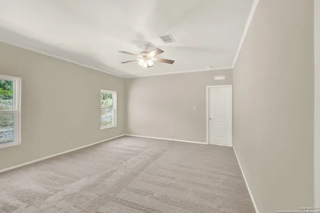 an empty room with windows and fan