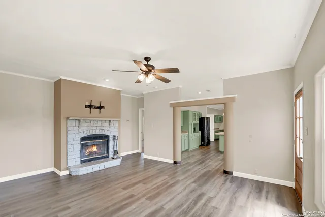 a view of an empty room with wooden floor fireplace and a window