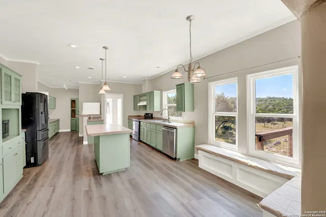 a large kitchen with sink a refrigerator and wooden floor