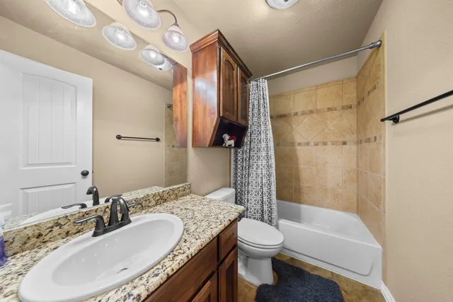a bathroom with a granite countertop sink a toilet a mirror a bathtub and shower