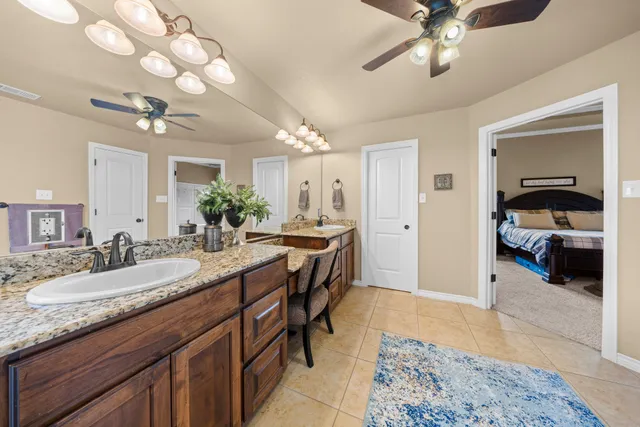 a en suite bathroom with a granite countertop sink and a mirror