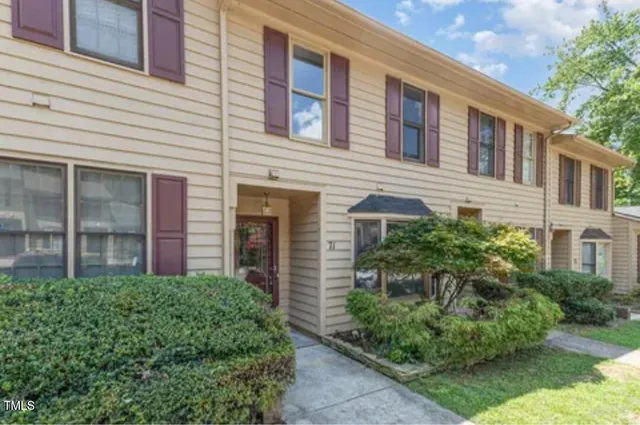 a front view of a house with plants and trees