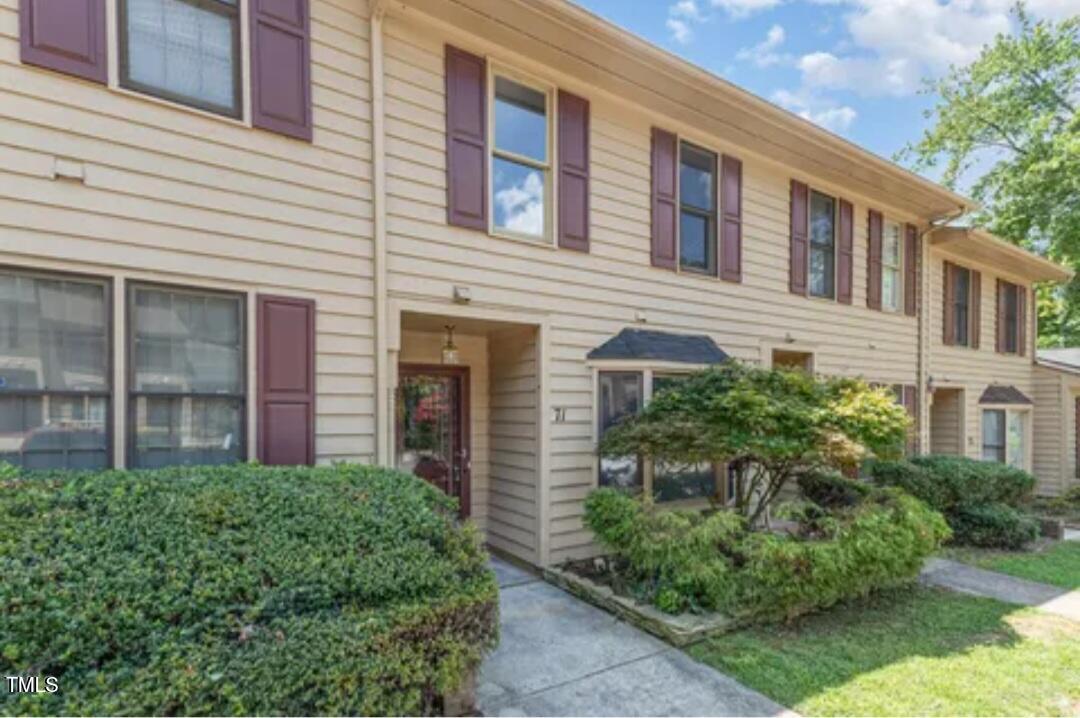 a front view of a house with plants and trees