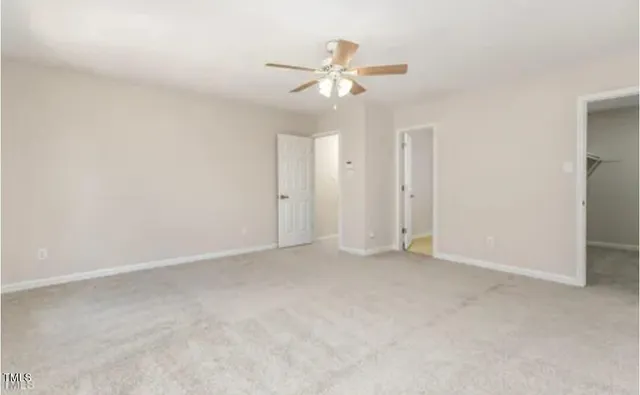 an empty room with a chandelier fan and windows