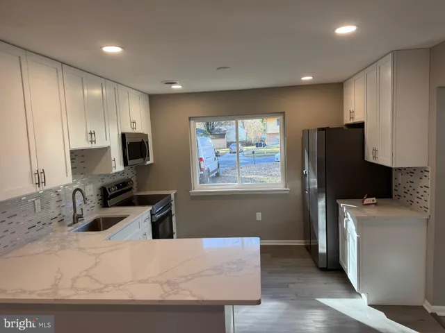 a kitchen with appliances a sink a counter top space and cabinets