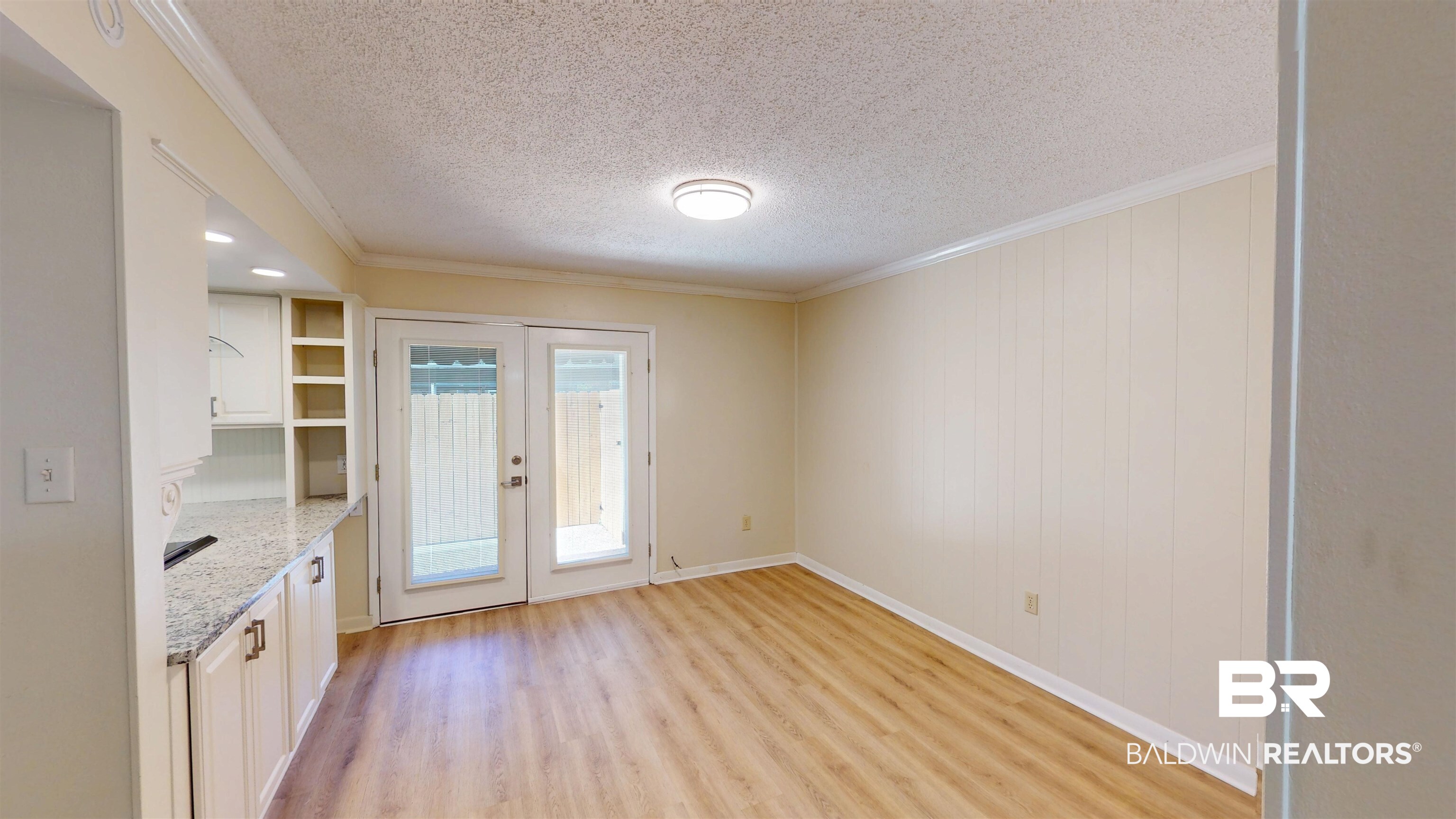 2901 Grant Street, Unit 902 Mobile, AL 36606 - Photo 10 of 35 Unfurnished dining area featuring ornamental molding, a textured ceiling, light wood-style floors, and french doors