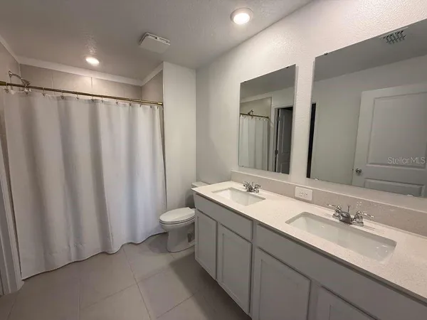 a bathroom with a double vanity sink toilet and a mirror