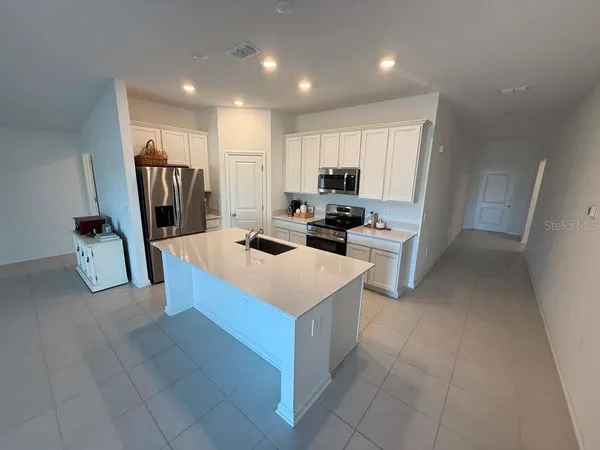 a kitchen that has a lot of white cabinets and stainless steel appliances