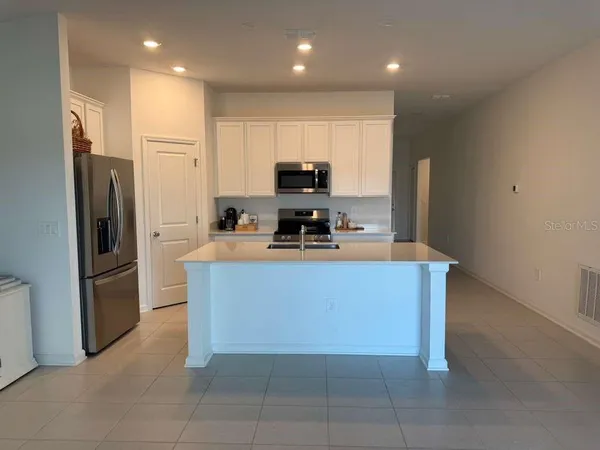 a kitchen with granite countertop a refrigerator and a stove top oven