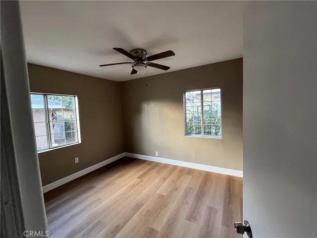 a view of an empty room with a window and wooden floor