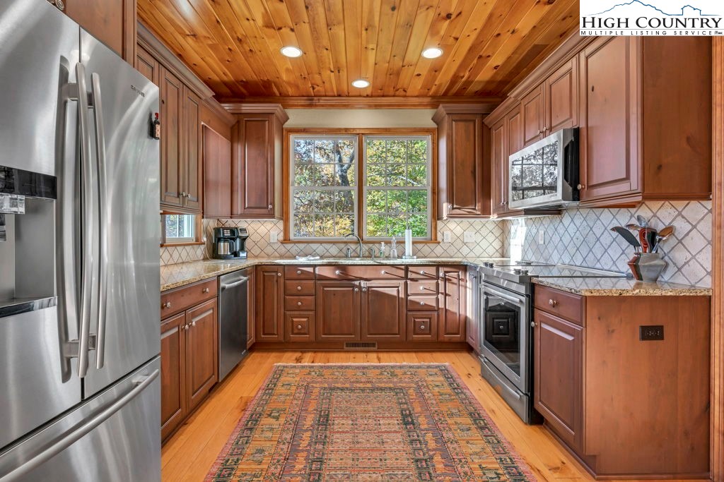 3664 Elk Ridge Road Ferguson, NC 28624 - Photo 20 of 46 a kitchen with stainless steel appliances granite countertop a refrigerator a sink dishwasher a stove top oven and a dining table with wooden floor