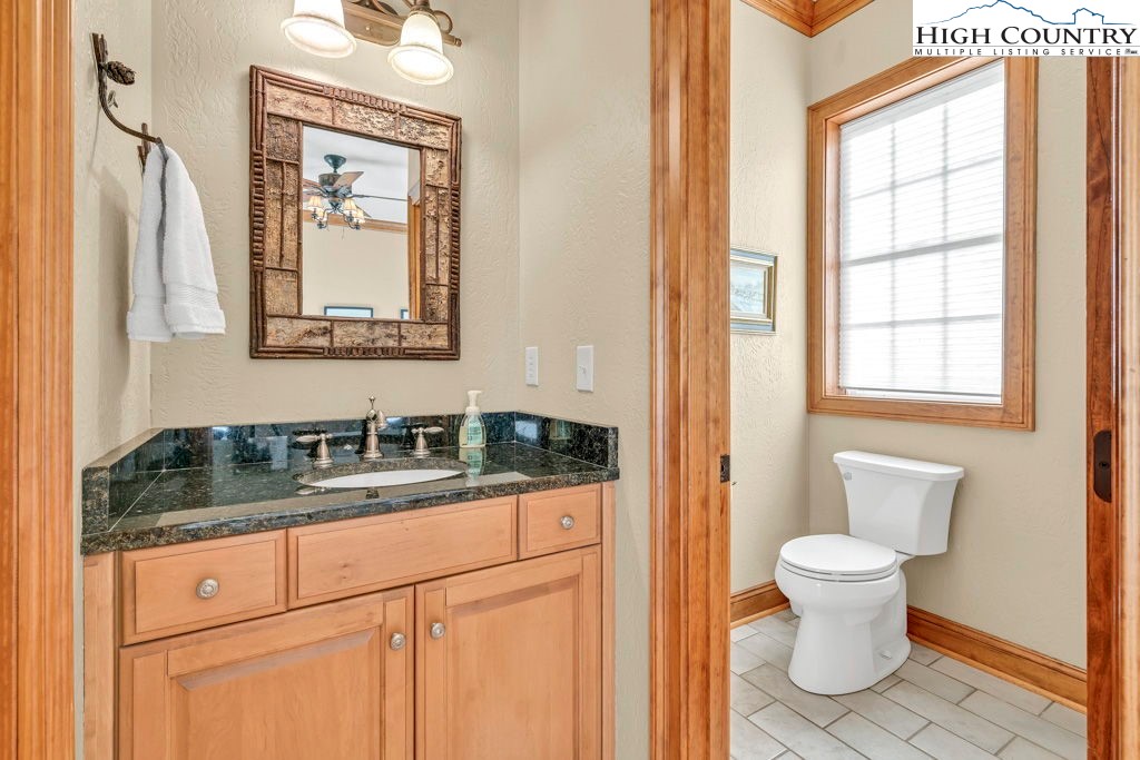 3664 Elk Ridge Road Ferguson, NC 28624 - Photo 37 of 46 a bathroom with a granite countertop toilet sink and mirror