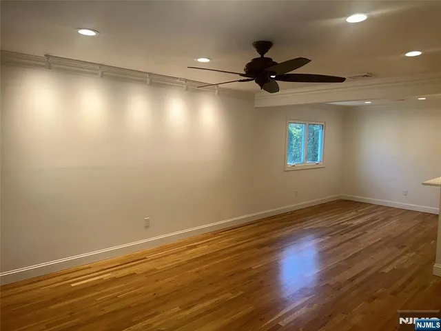 an empty room with wooden floor fan and windows