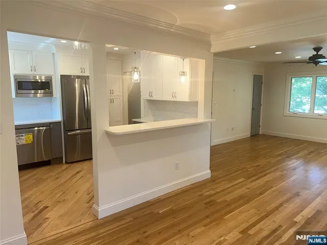 an empty room with wooden floor and a kitchen
