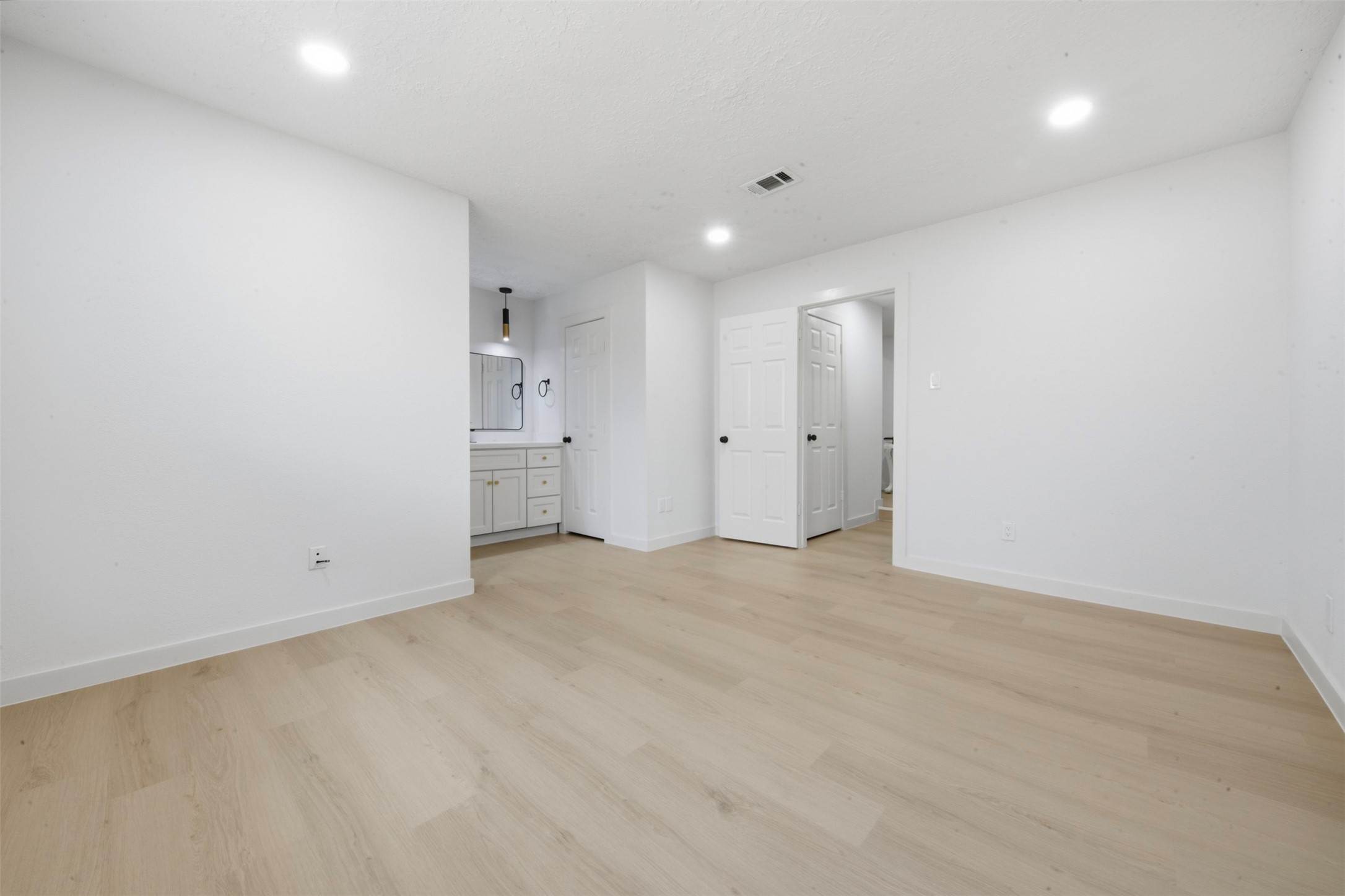 9518 Landry Boulevard Spring, TX 77379 - Photo 14 of 38 Spacious, light-filled bedroom with modern recessed lighting, sleek hardwood flooring, and a stylish en-suite vanity area.