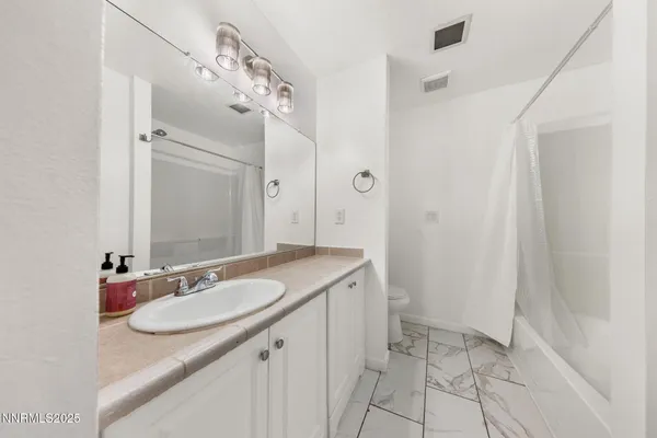 a bathroom with a granite countertop sink a mirror and a shower