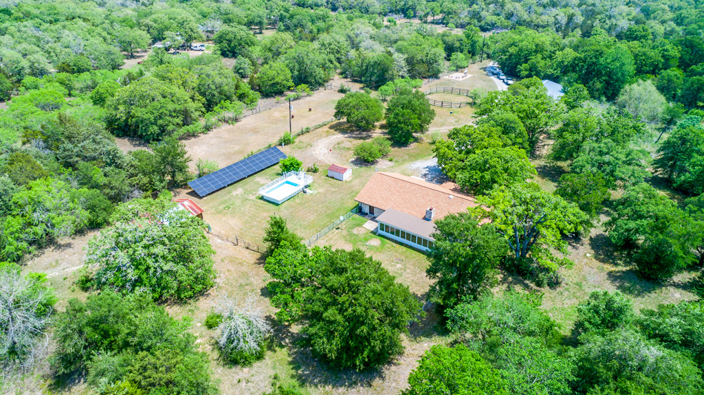 an aerial view of residential house with outdoor space and trees all around