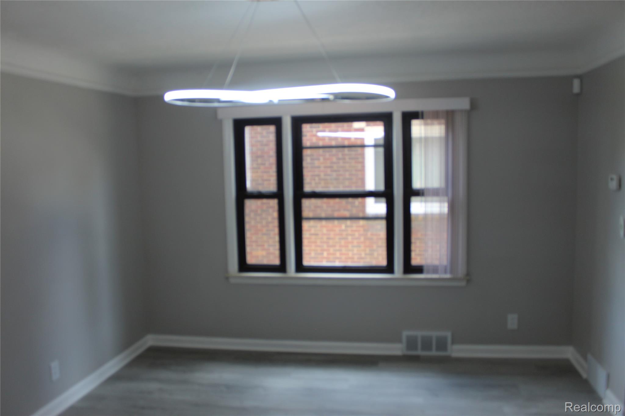 5543 Balfour Road Detroit, MI 48224 - Photo 21 of 54 Spacious room featuring a contemporary linear chandelier, large window with black framing, wood-finish flooring, and crown molding
