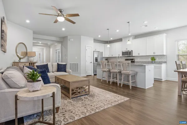 a living room with furniture kitchen view and a wooden floor