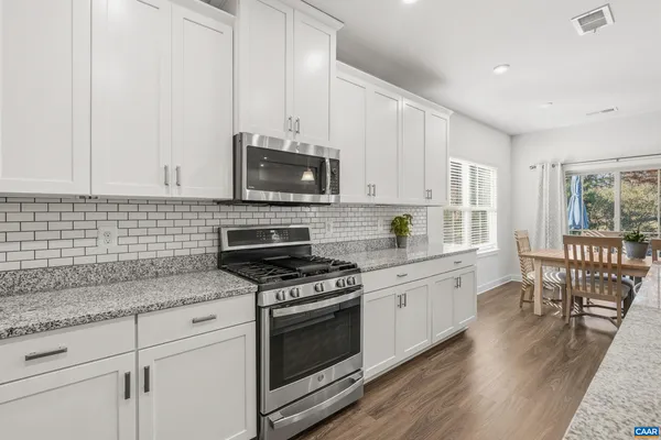 a kitchen with granite countertop a stove sink microwave and cabinets