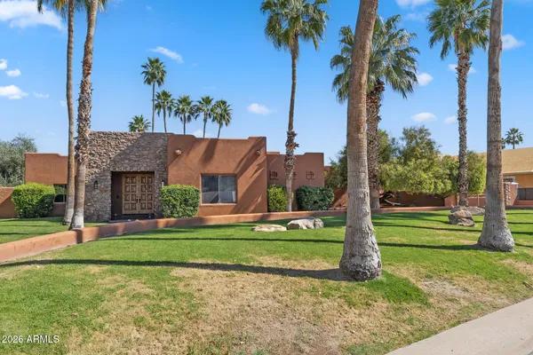 a view of a house with a yard and palm trees