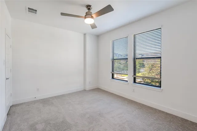 an empty room with a window and a ceiling fan