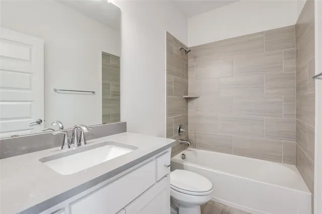 a bathroom with a granite countertop bathtub shower sink vanity mirror and toilet