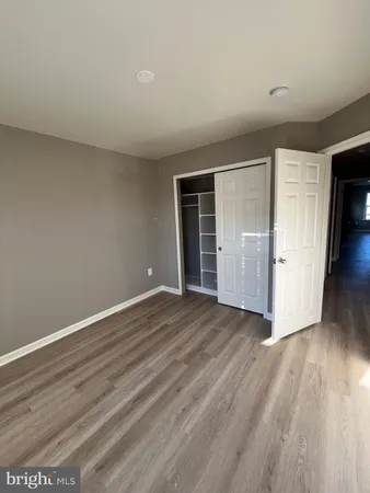 a view of an empty room with wooden floor and closet