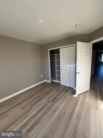 a view of an empty room with wooden floor and closet