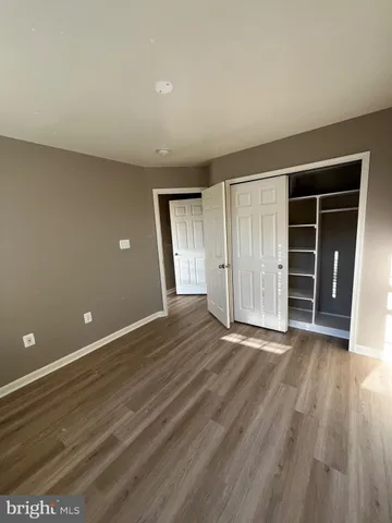 a view of an empty room with wooden floor and closet