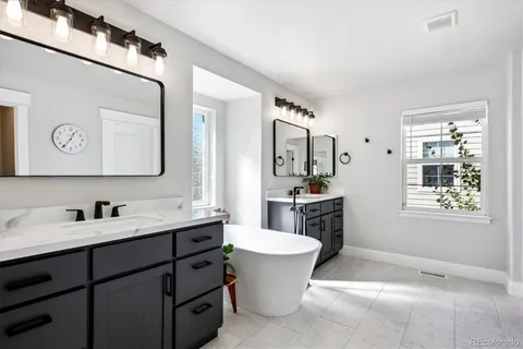 a bathroom with a double vanity sink mirror and bathtub