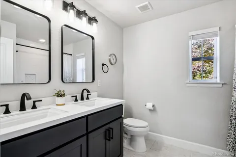 a bathroom with a toilet sink double vanity and mirror